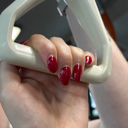 Hand with red nail polish holding a white handle