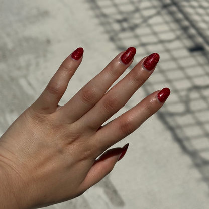 Hand with red nail polish on a concrete surface