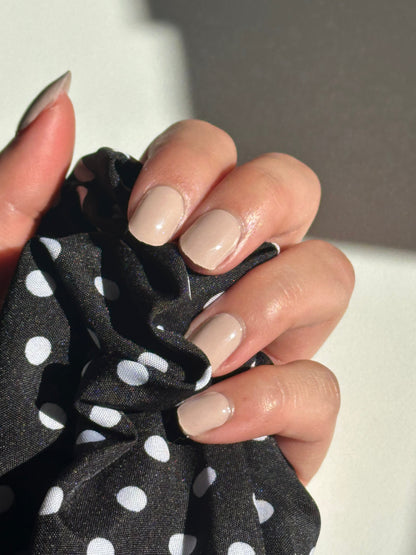 Hand holding a black scrunchie with white polka dots, close-up shot.