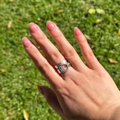 Hand wearing a ring with a green grass background