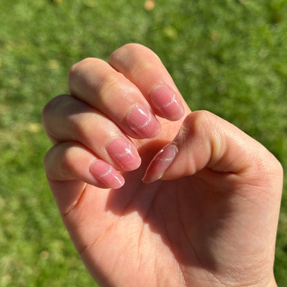 Close-up of a hand with manicured nails against a grassy background