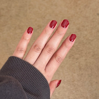 Hand with red nail polish on a beige background